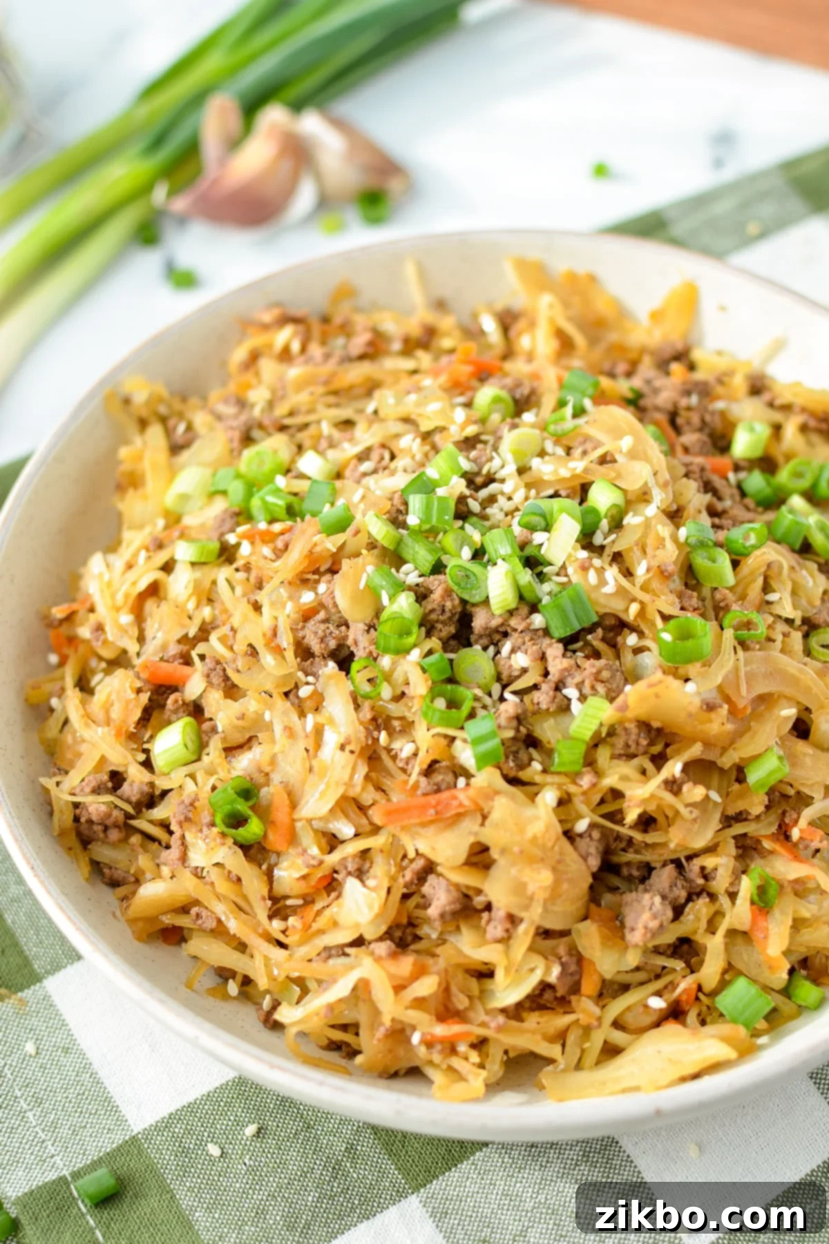 A bowl of egg roll in a bowl topped with green onions and sesame seeds, ready to be enjoyed.
