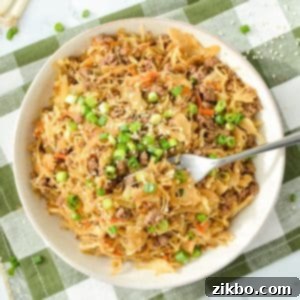 A bowl filled with cabbage and ground beef stir fry, garnished with green onions and sesame seeds.