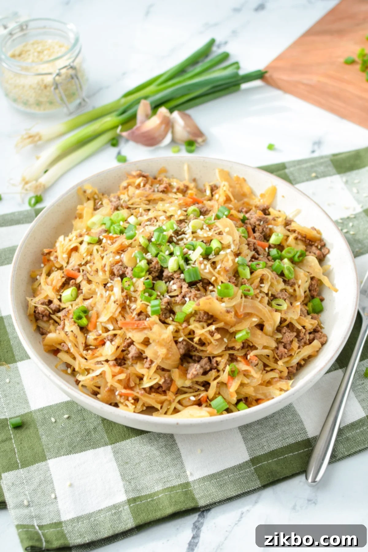 A close-up shot of egg roll filling in a bowl, garnished with fresh green onions and sesame seeds.