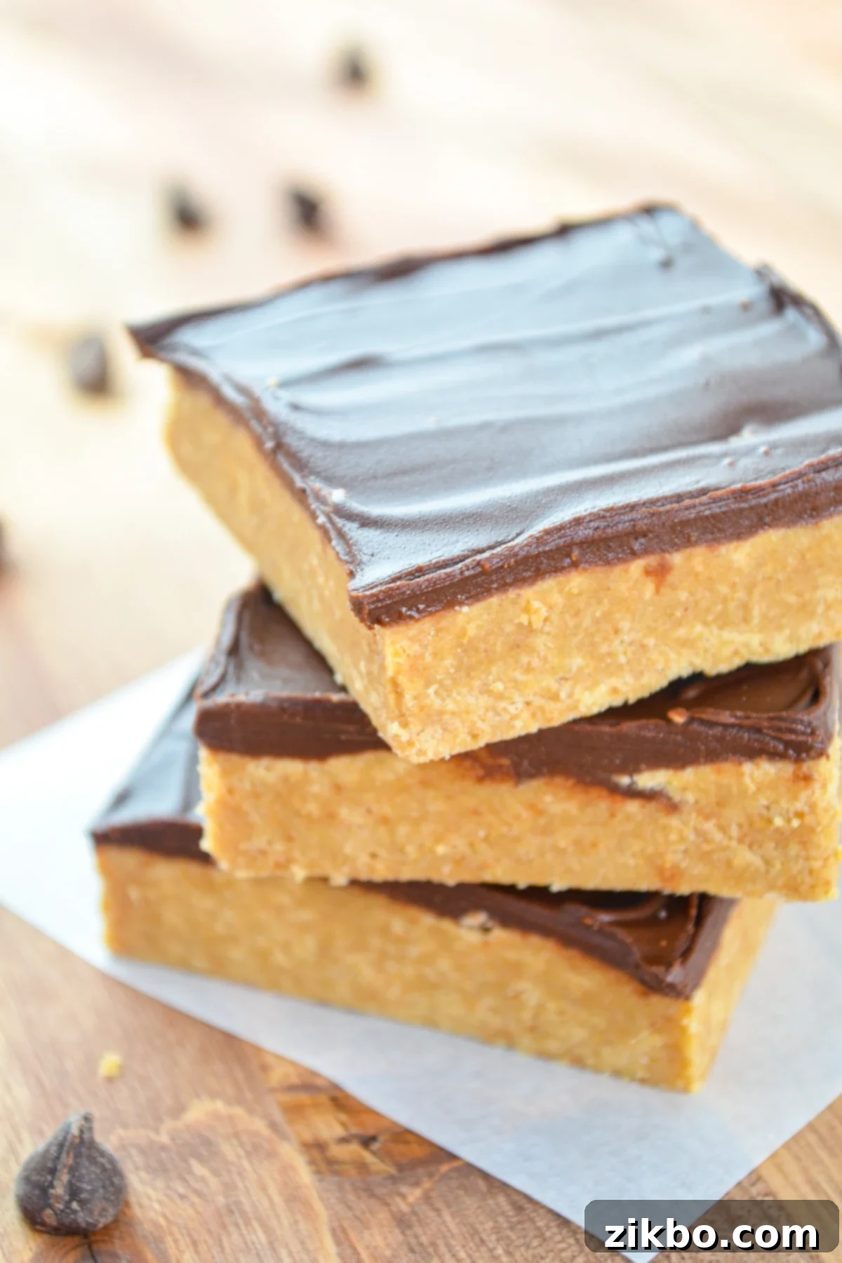 A stack of three no bake peanut butter bars, showcasing the distinct layers of chocolate and peanut butter.