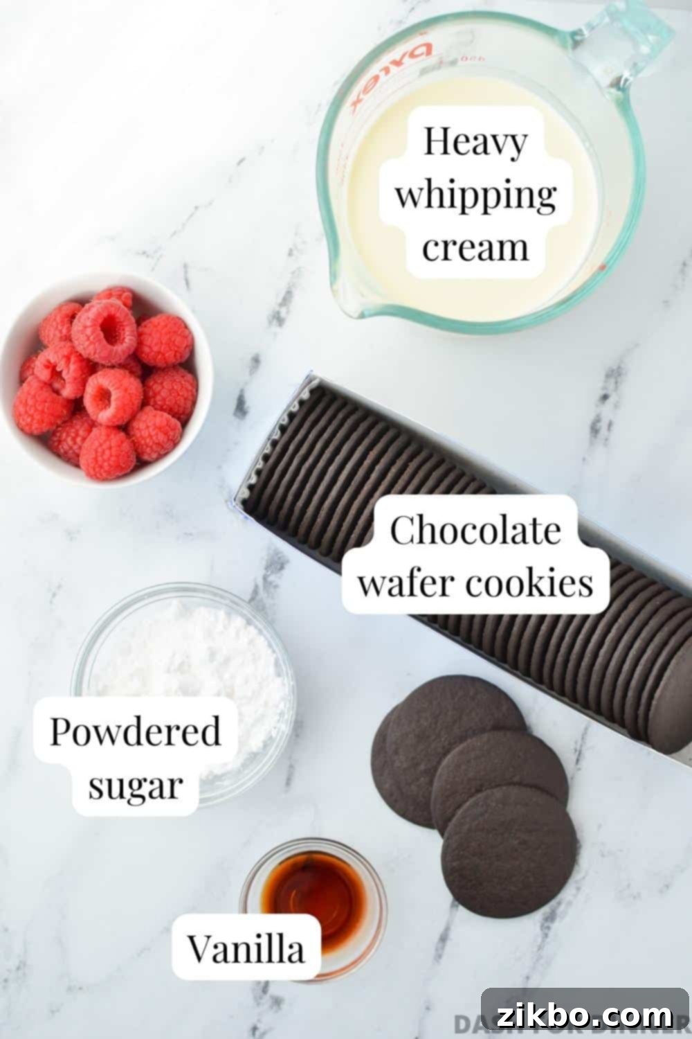 The four essential ingredients for icebox cake: chocolate wafer cookies, heavy cream, vanilla extract, and powdered sugar, laid out on a kitchen counter.