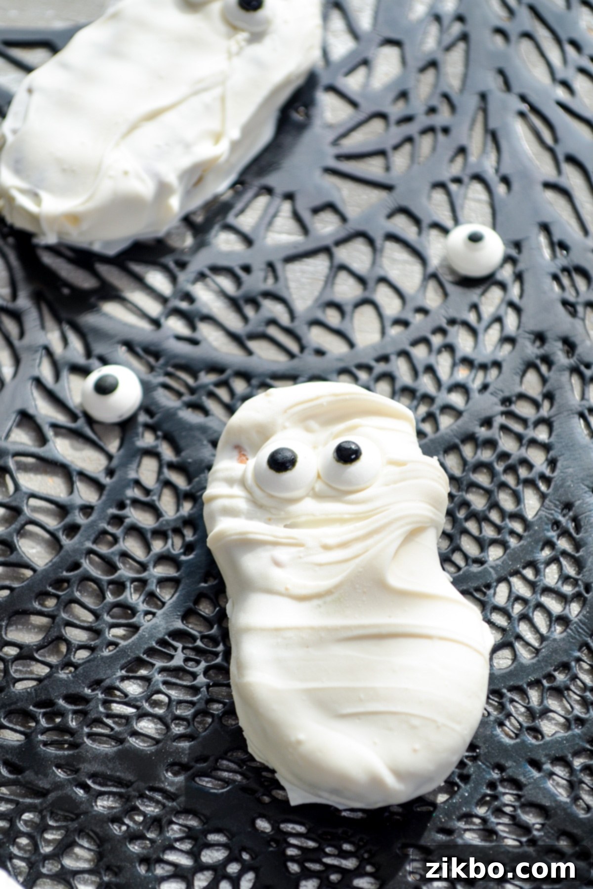 Halloween themed cookies, including Nutter Butter Ghosts, on a black and white striped background.