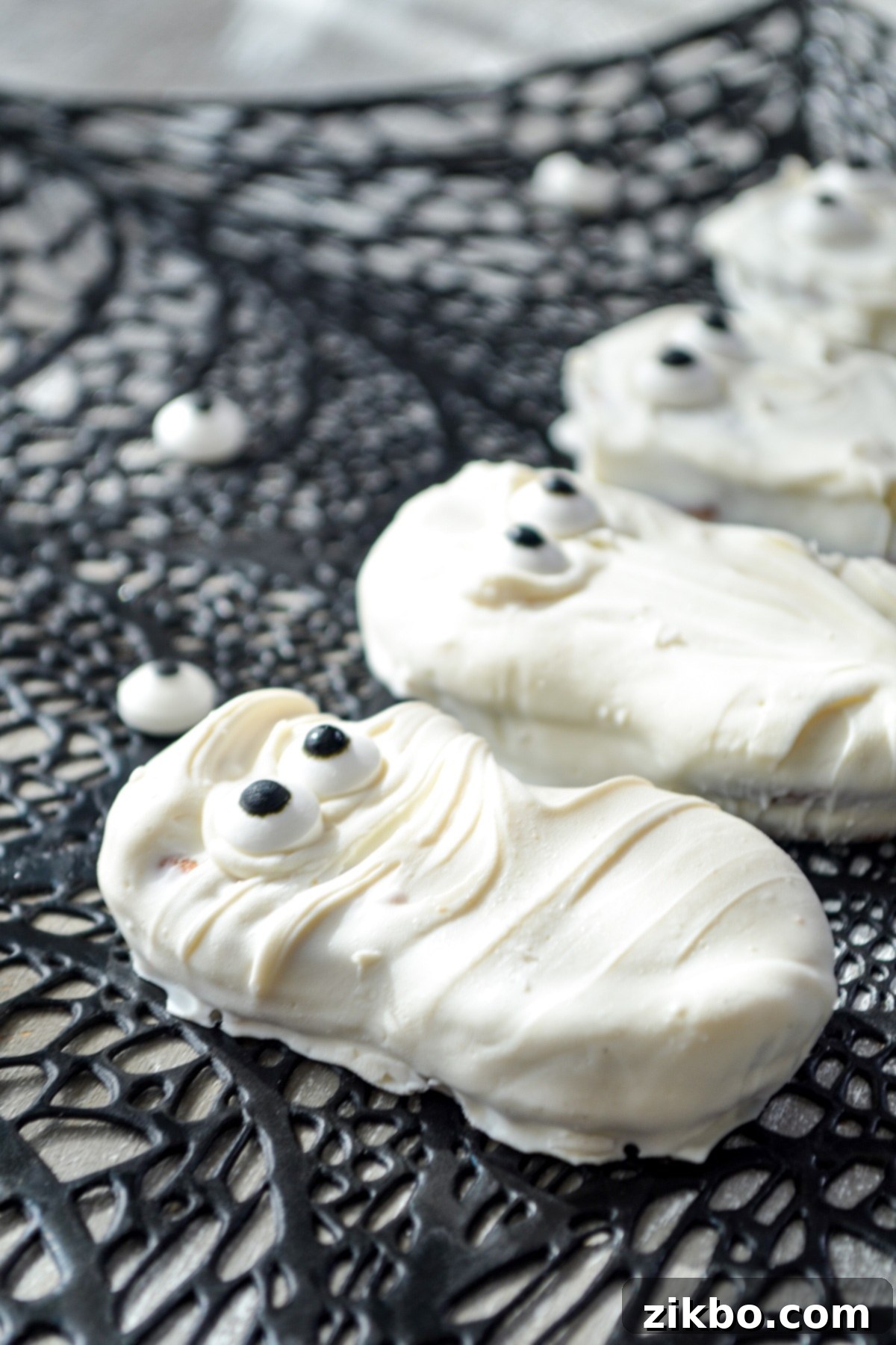 A line up of freshly made Nutter Butter Ghost cookies with candy eyes, ready to chill.