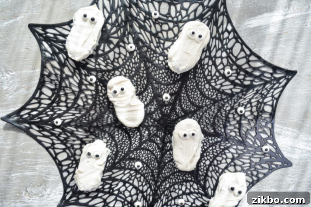 Finished Nutter Butter ghost cookies arranged on a festive spiderweb placemat.