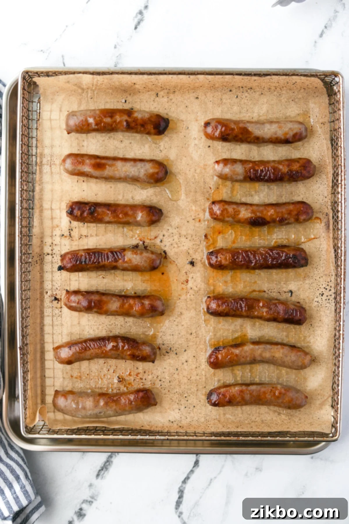 An air fryer tray filled with perfectly cooked, golden-brown sausage links.