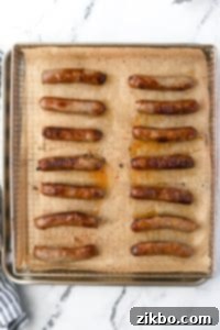 An air fryer tray filled with cooked sausage links, golden brown and juicy.