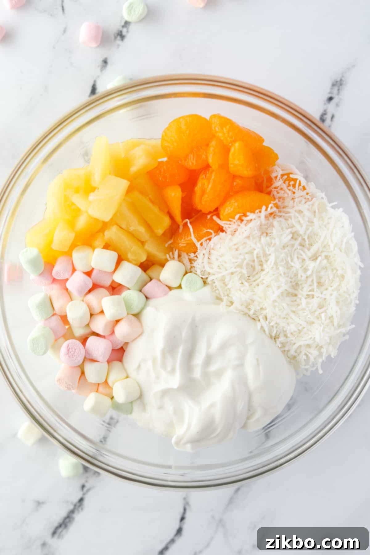 A bowl with 5 segments: mandarin oranges, pineapple, marshmallows, coconut, and yogurt.