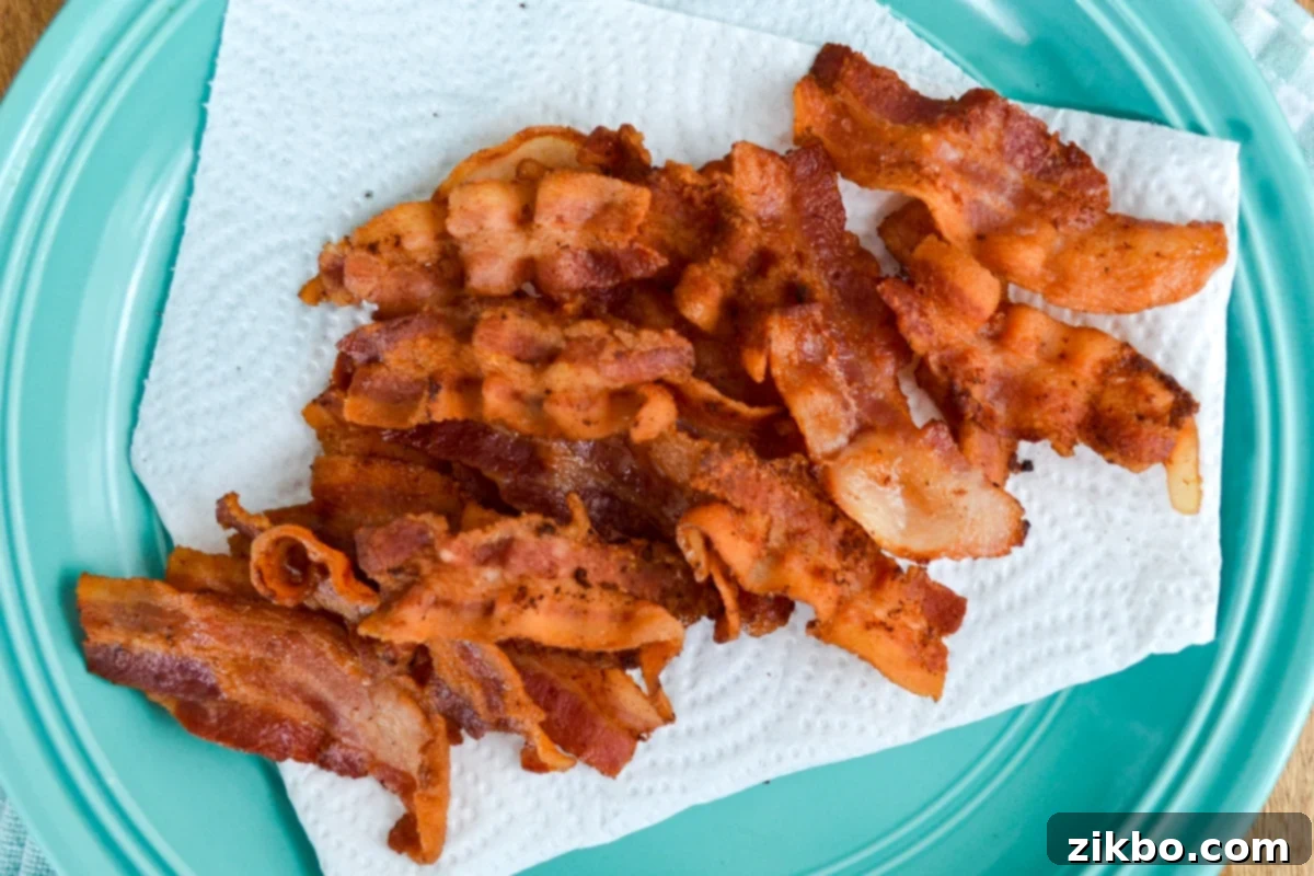 Crispy Instant Pot bacon slices draining on a paper towel lined plate, ready for serving.