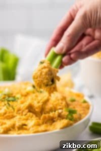 Dipping a celery stick into a bowl of buffalo chicken dip.