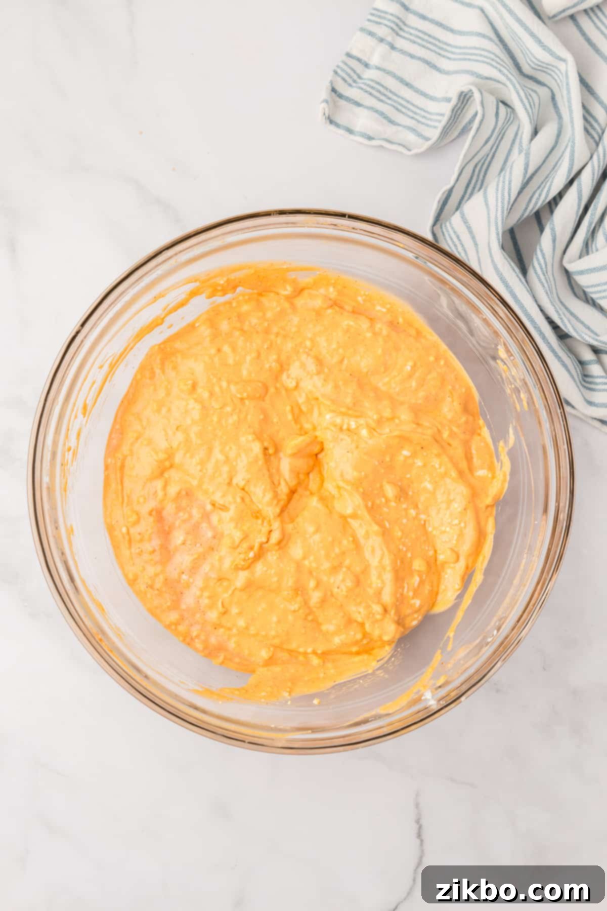 A large mixing bowl containing the smooth, creamy, and orange-tinted buffalo dip base.