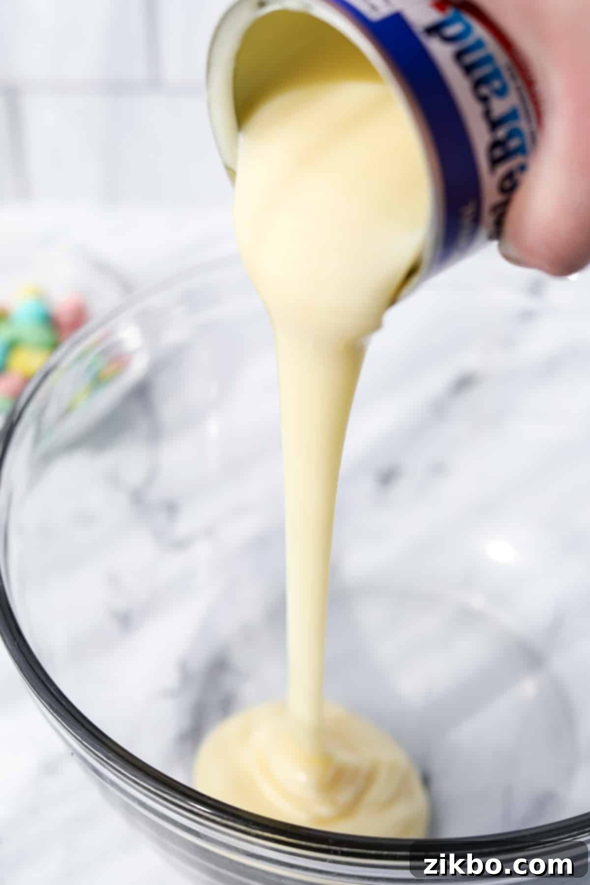 Pastel Egg Crunch Ice Cream 4 Sweetened condensed milk being poured into a mixing bowl, ready for the no-churn ice cream base.