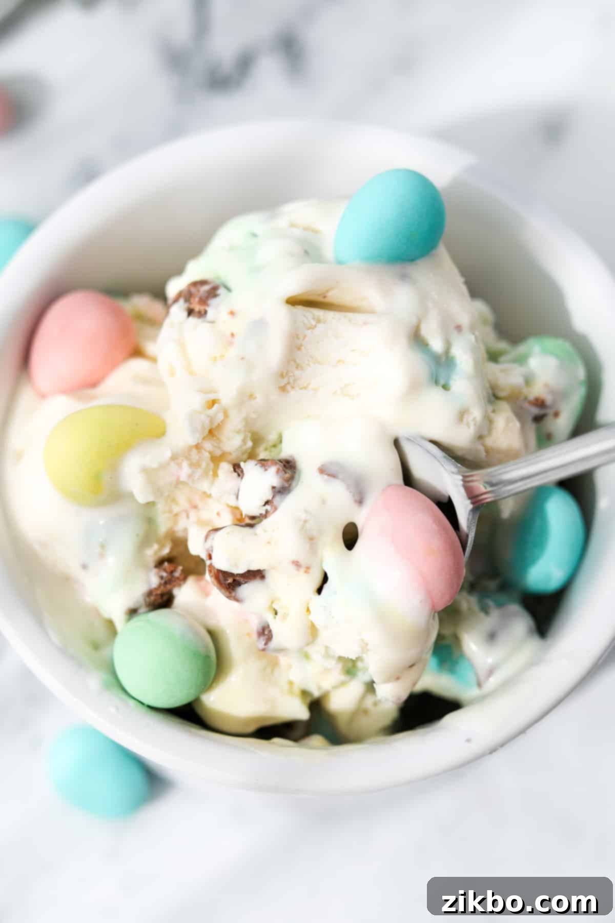 Pastel Egg Crunch Ice Cream 9 A delightful close-up of a spoon resting inside a small bowl of creamy Mini Egg Ice Cream, ready to be enjoyed.