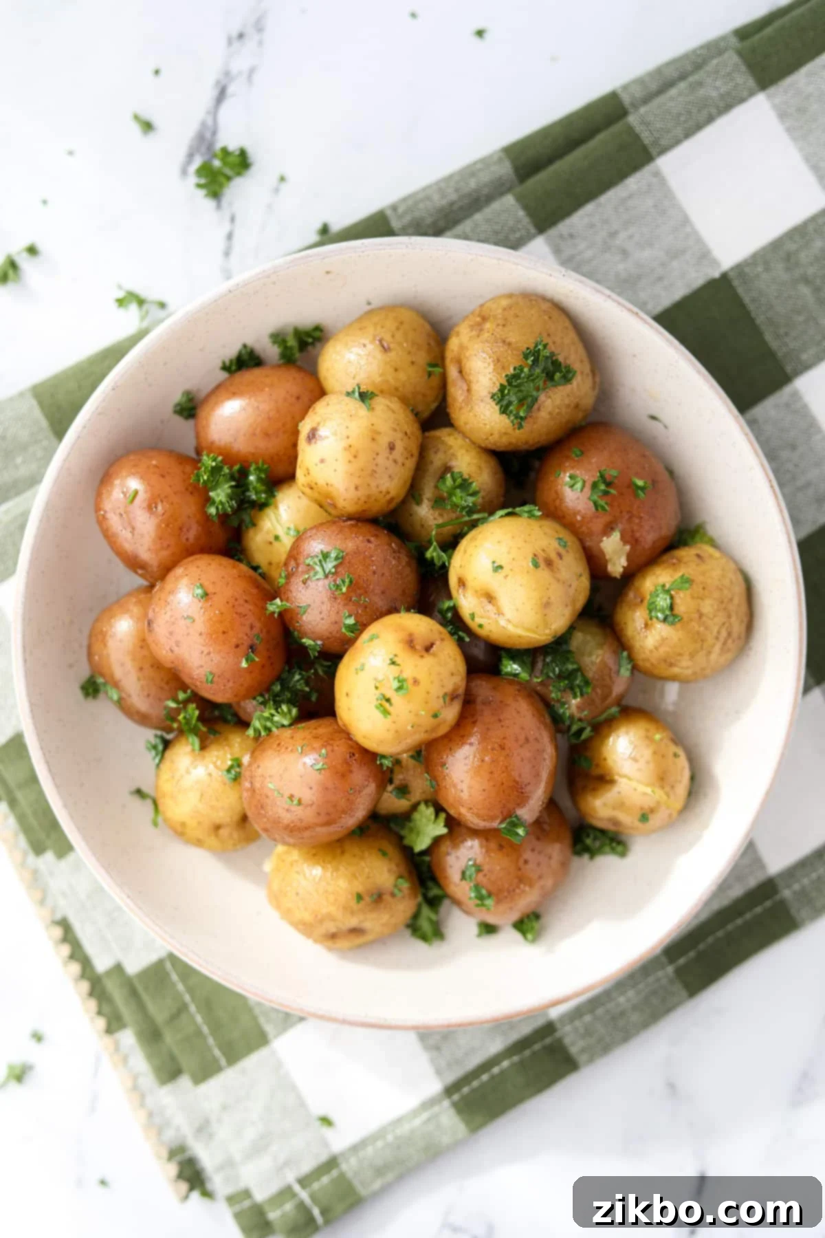 A bowl of buttered baby potatoes garnished with parsley.