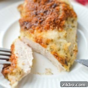 Creamy Parmesan Chicken 9 A fork taking a slice of chicken from a chicken breast.
