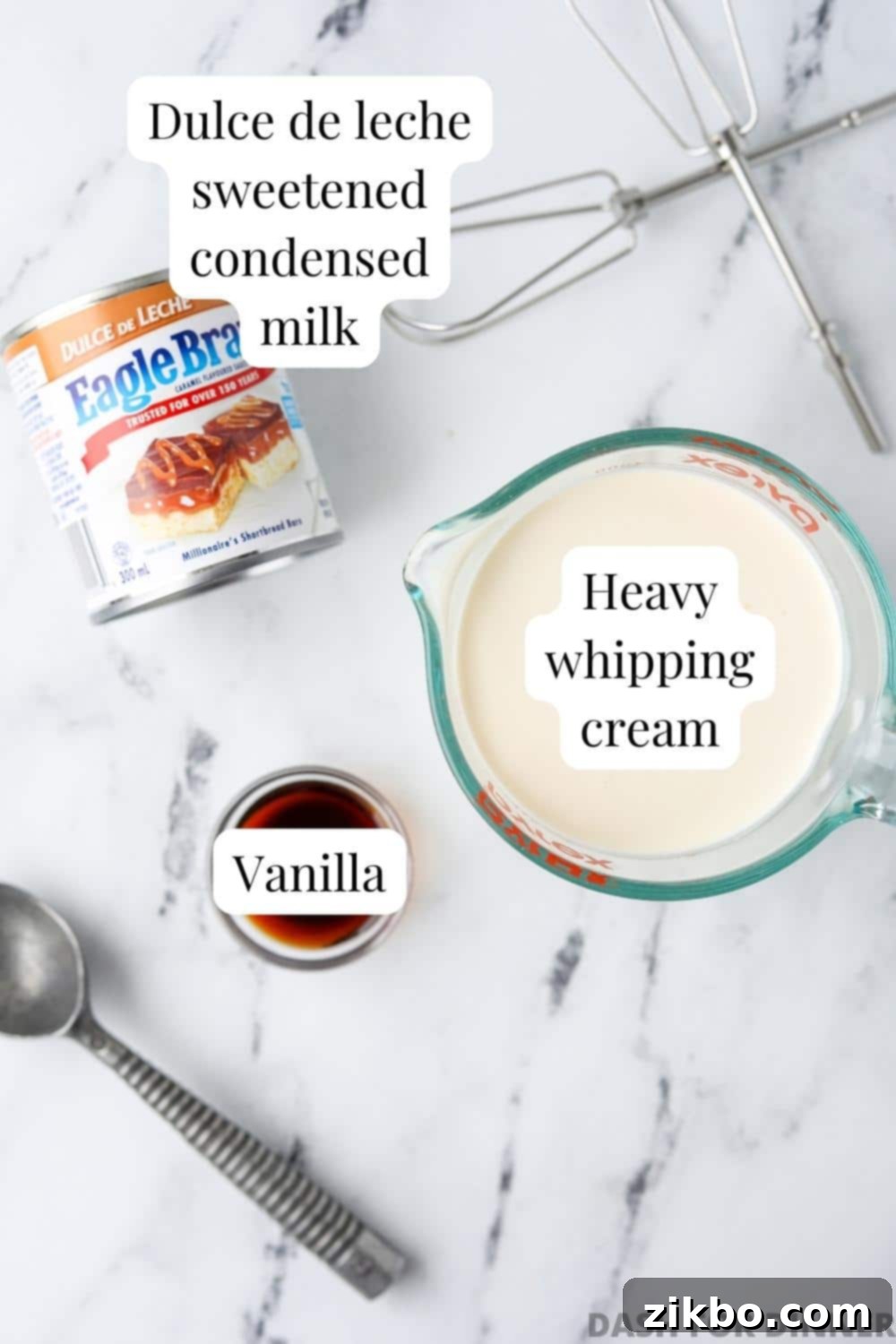 Decadent Dulce de Leche Ice Cream 3 The ingredients needed to make dulce de leche ice cream: dulce de leche, heavy cream, and vanilla extract are laid out on a wooden surface.