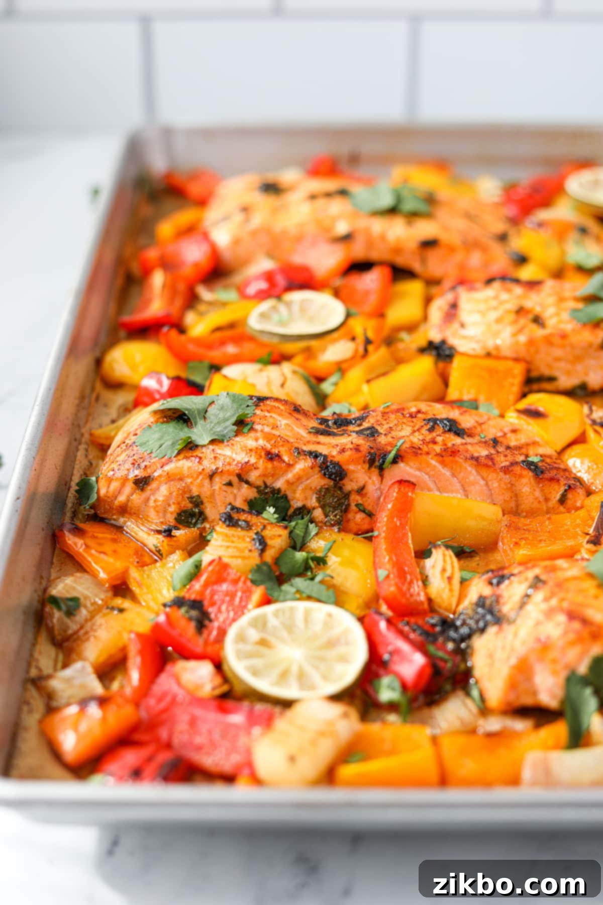 A sheet pan filled with perfectly cooked salmon fillets and roasted bell peppers and onions, fresh out of the oven.