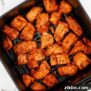 An air fryer basket filled with perfectly cooked and crispy salmon bites.
