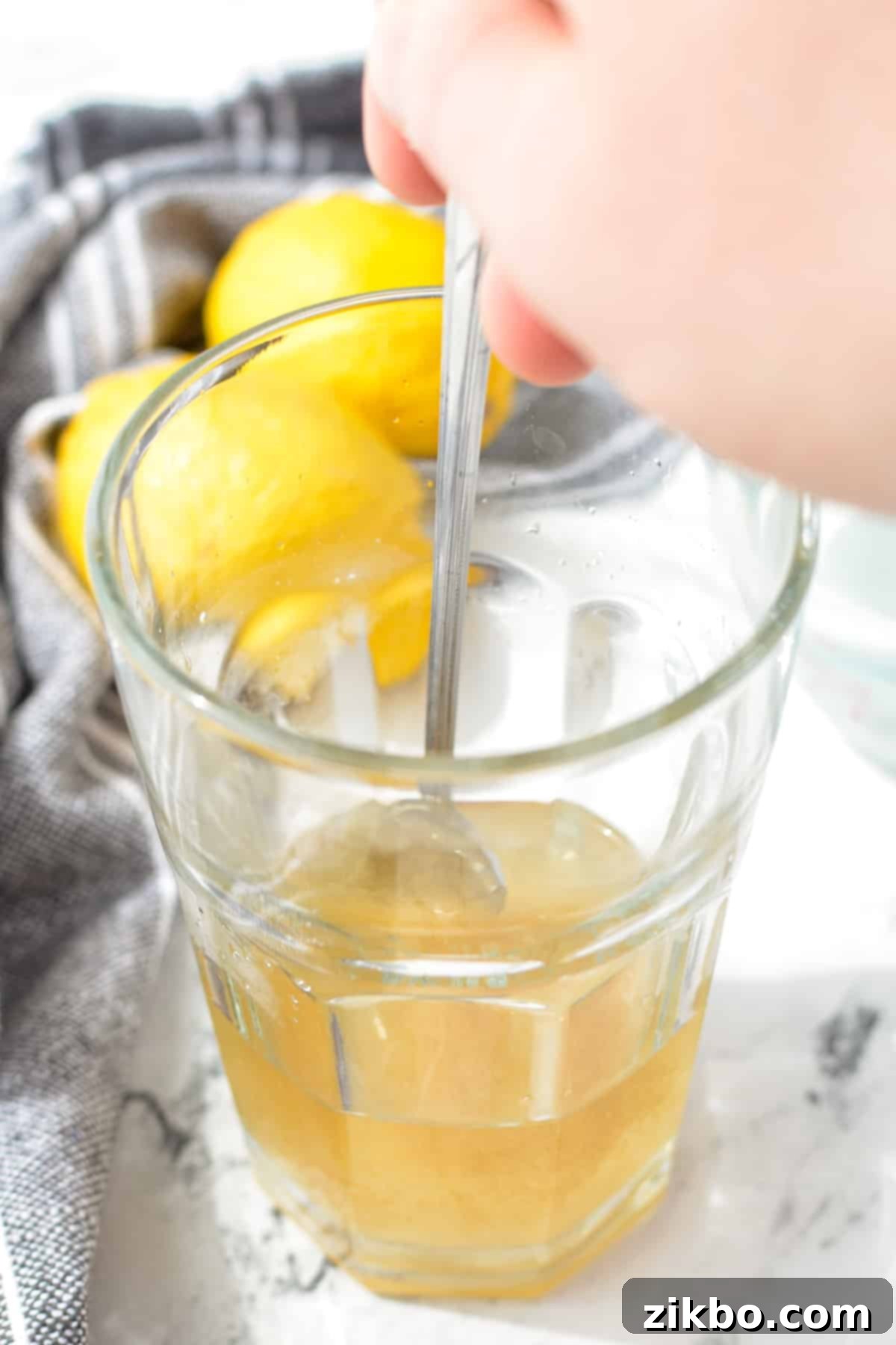 Stirring a glass with a long spoon to dissolve sugar in hot water.