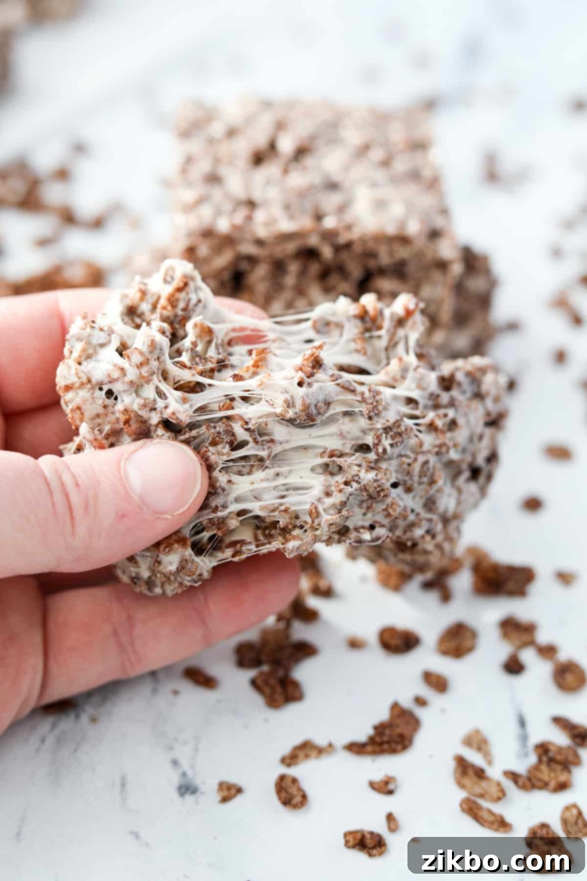 Pulling a cereal treat apart to show the gooey marshmallow.