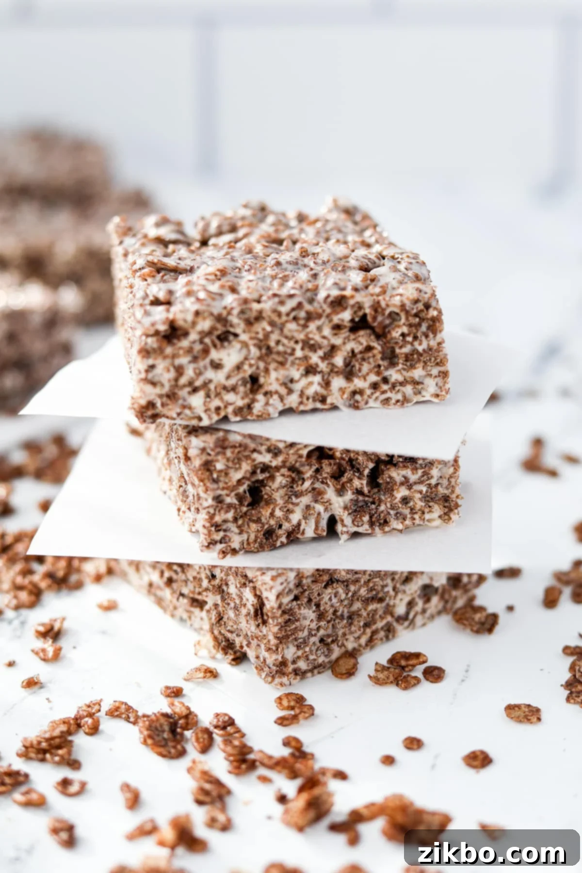 A stack of three chocolate cereal treats on a white surface.