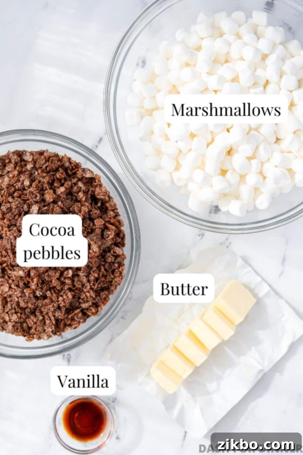 A bowl of marshmallows, Cocoa pebbles cereal, butter, and vanilla.