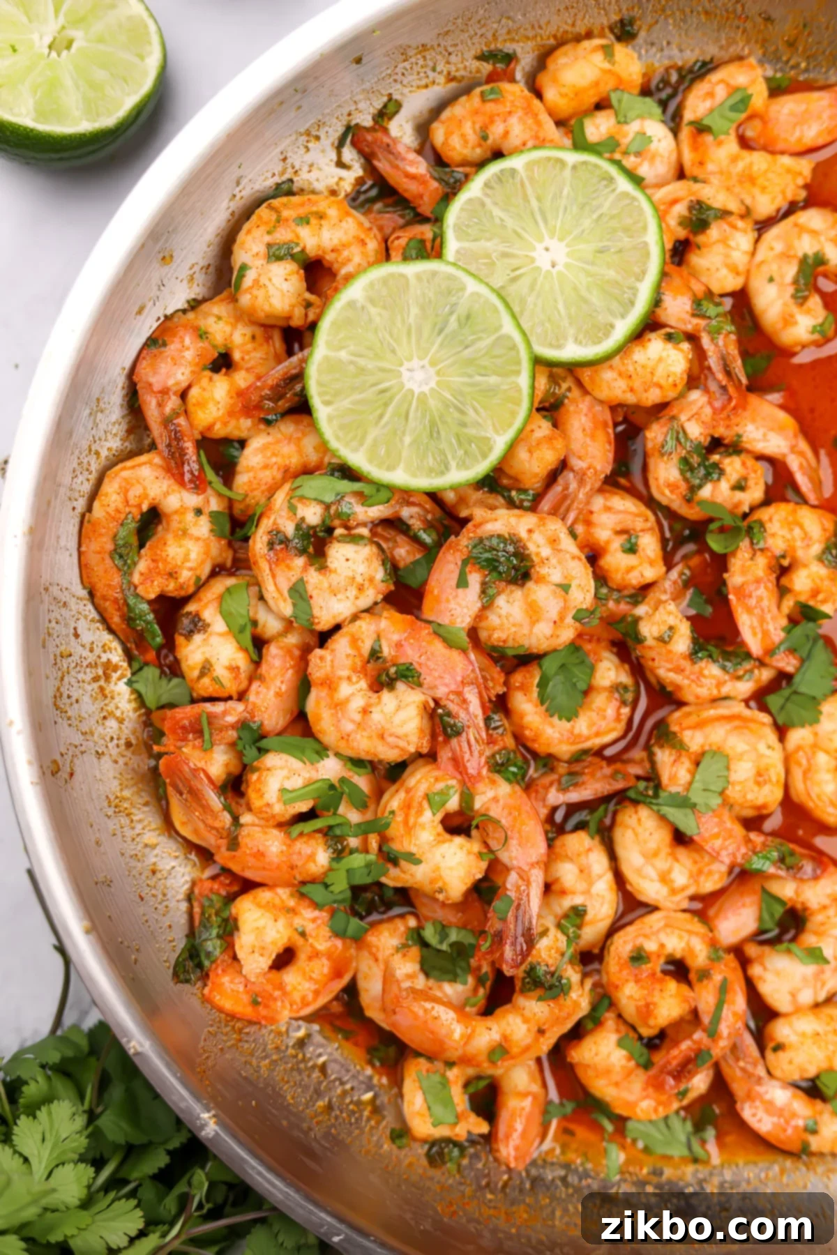 A skillet filled with perfectly cooked cilantro lime shrimp, glistening with sauce and garnished with fresh cilantro.