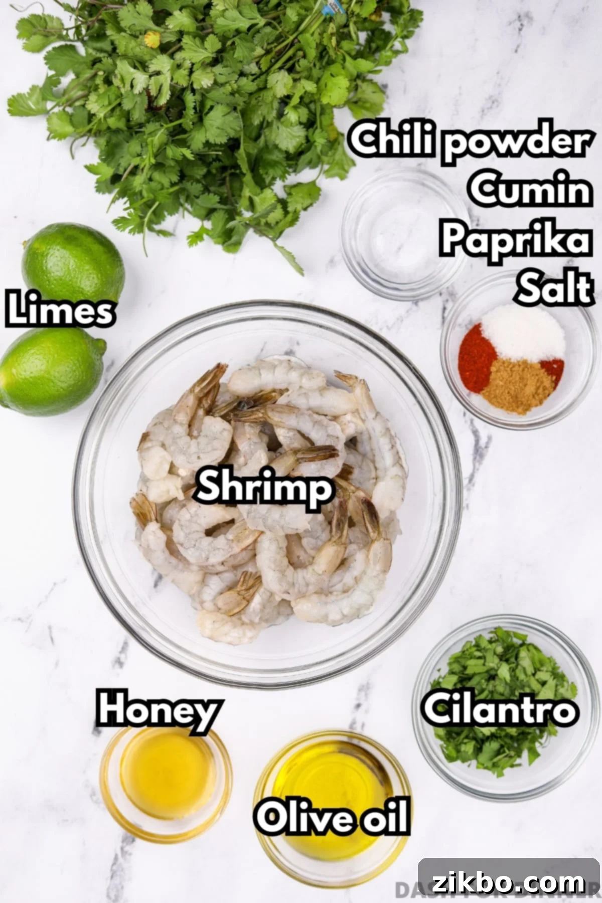 A collection of ingredients for cilantro lime shrimp, including fresh limes, cilantro, raw shrimp, and spices.