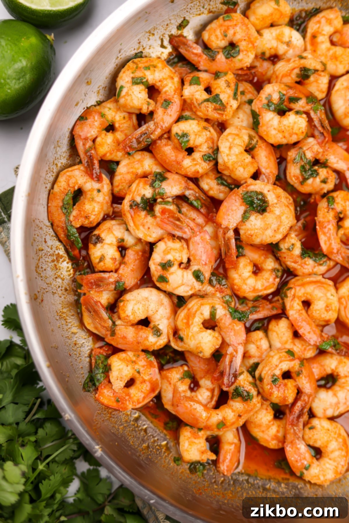 A skillet featuring cooked shrimp tossed in a vibrant red sauce, ready to be served.