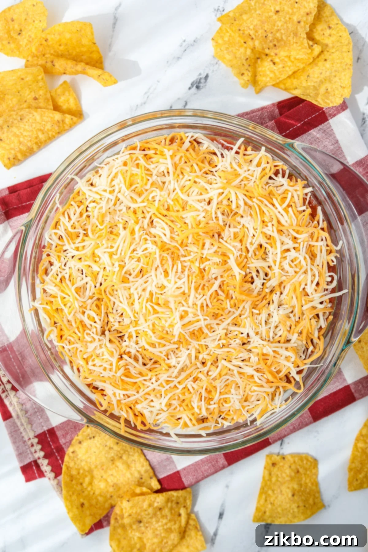 A baking dish with the 4-layer dip covered in shredded cheese, ready to be served.
