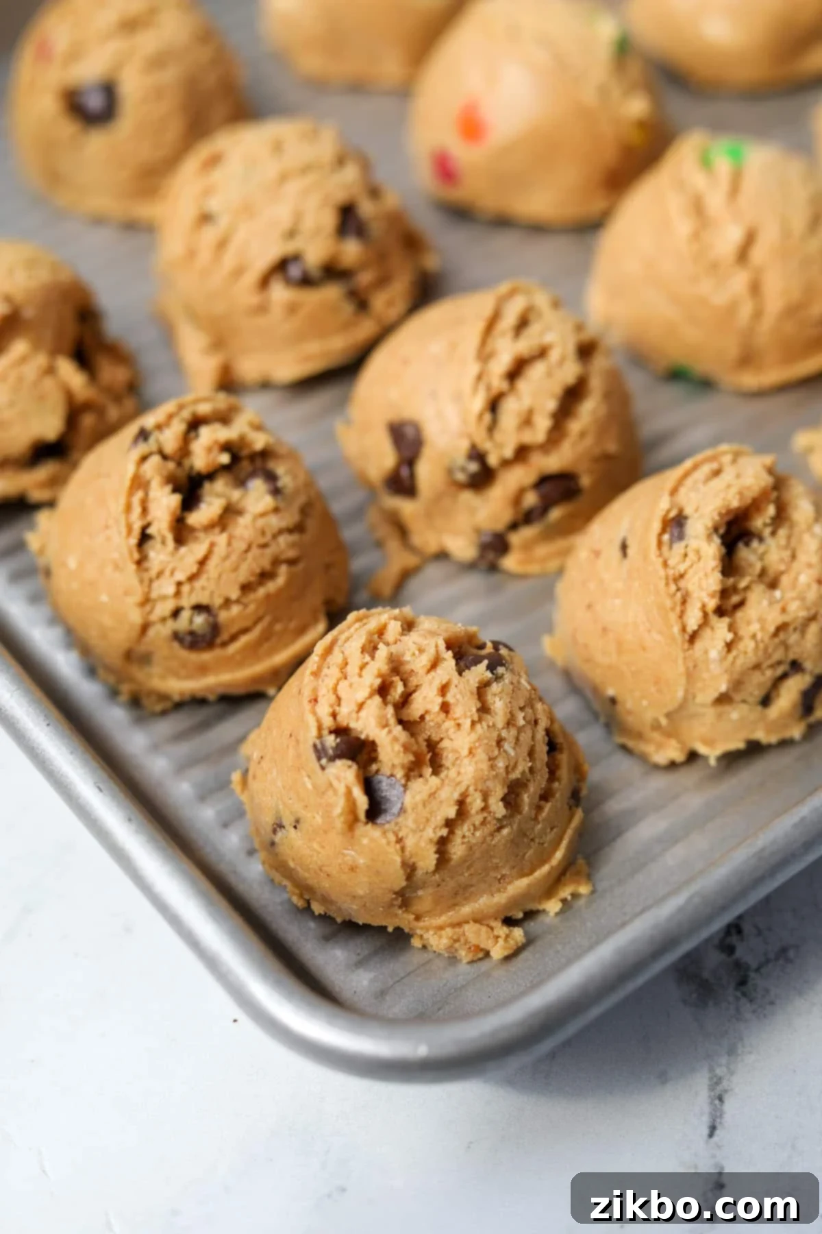 Protein Cookie Dough 2 Scoops of delicious protein cookie dough ready to be chilled on a baking sheet, featuring mix-ins like chocolate chips.