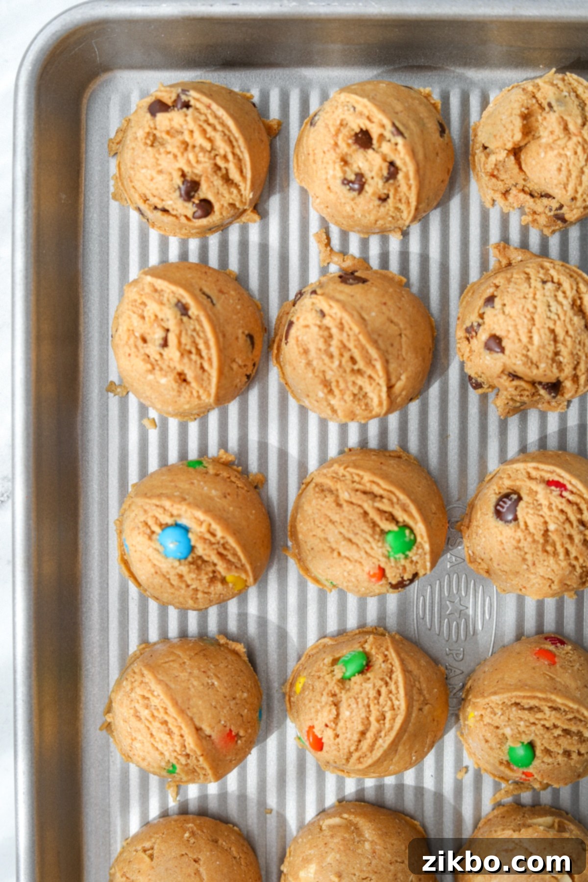 Protein Cookie Dough 11 A baking sheet showcases rows of perfectly scooped, high-protein cookie dough portions, each with visible chocolate chips.