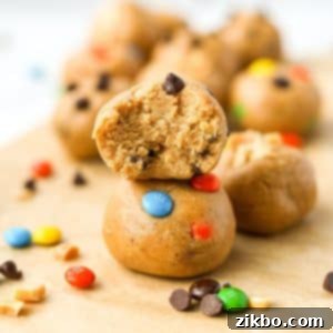 Two cookie dough balls stacked on top of each other, with a bite taken out of the top one.