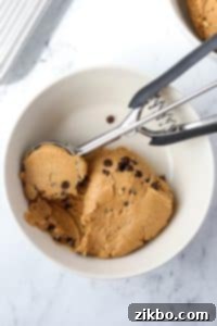 A bowl with protein cookie dough being scooped by a cookie scoop.