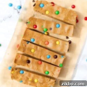 Protein-Packed Monster Cookie Bars 14 6 protein bars on a piece of parchment paper, topped with m&m candies, showcasing a delightful and healthy snack.