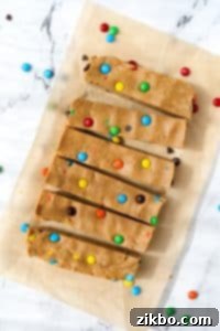 6 perfectly sliced protein bars arranged on a sheet of parchment paper, highlighting their vibrant M&M toppings.