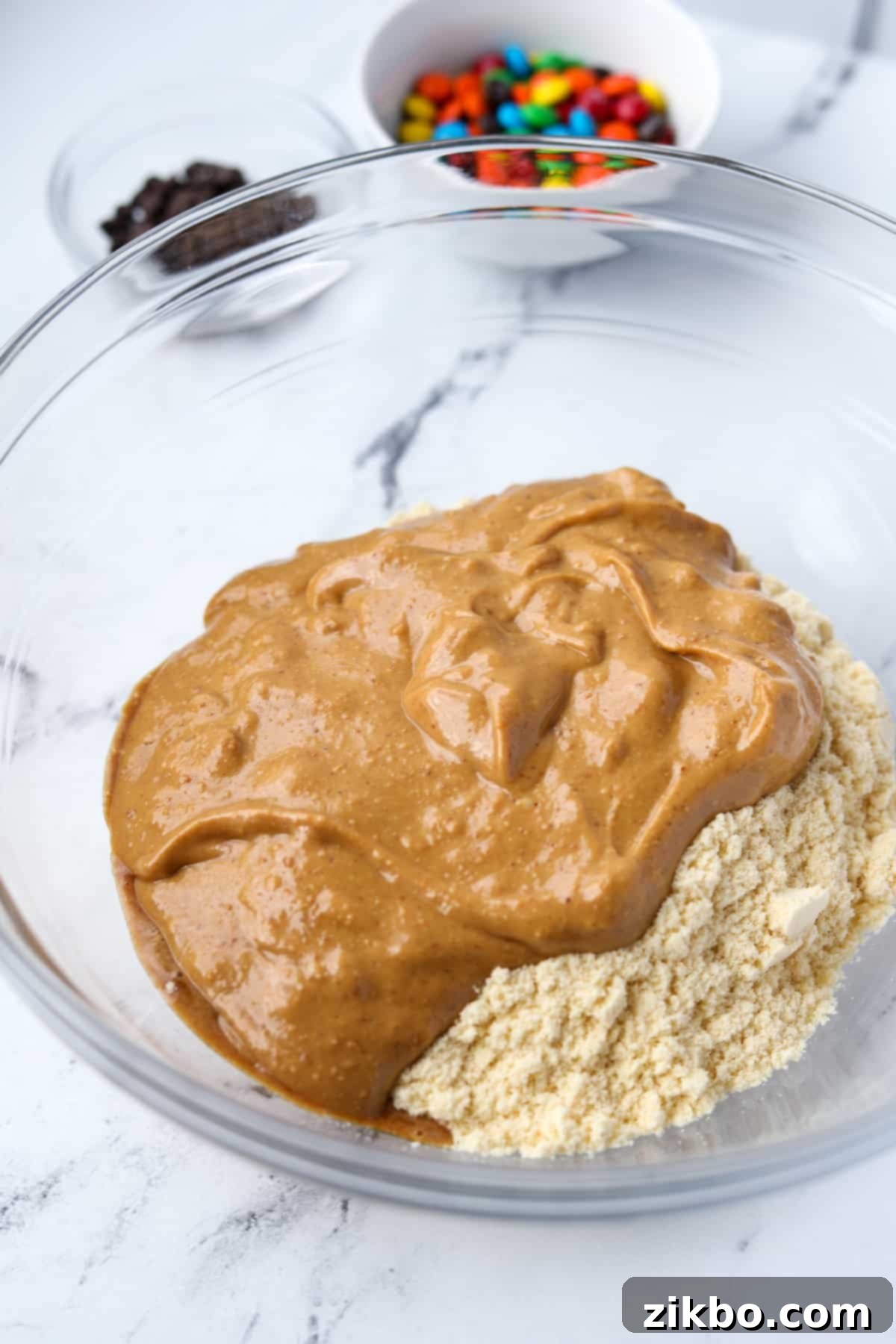 Protein-Packed Monster Cookie Bars 4 A bowl containing oat flour, natural peanut butter, and vanilla protein powder, ready to be mixed.