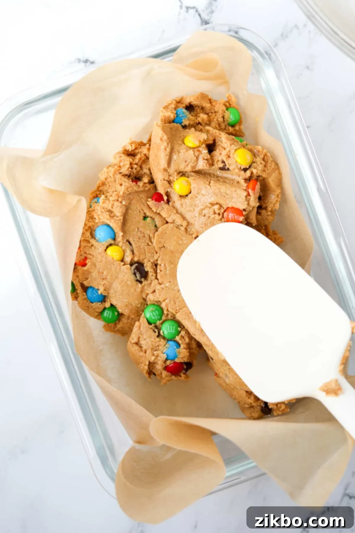 Protein-Packed Monster Cookie Bars 8 Spreading the protein bar dough into a parchment-lined baking dish.