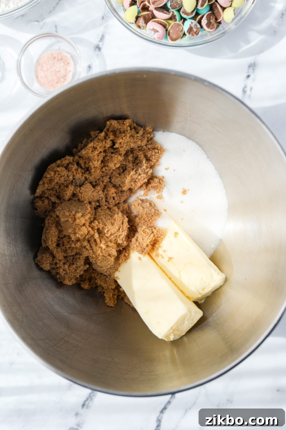 A stand mixer bowl with butter, brown sugar, and white sugar in it.