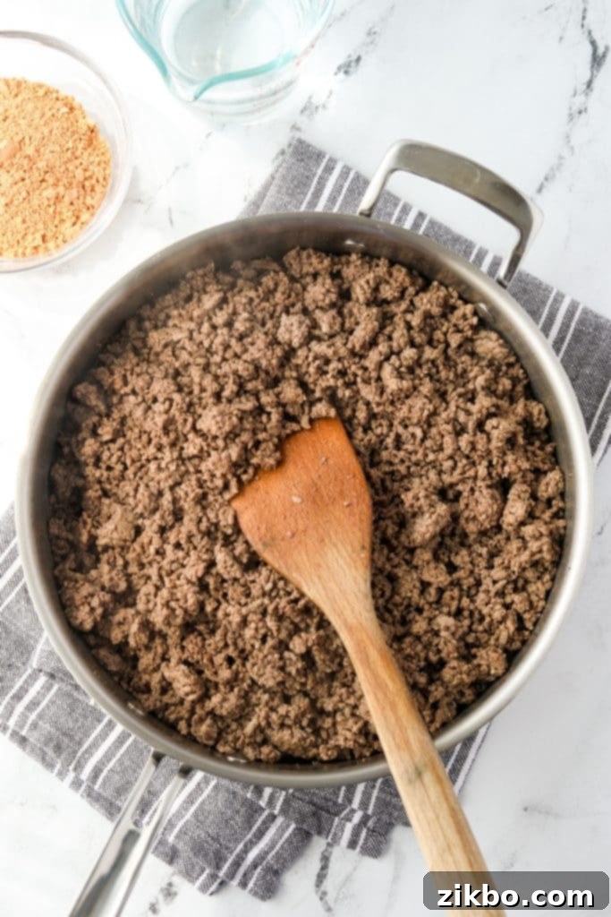 A skillet with ground beef browning evenly over medium heat.