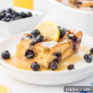 Overnight Brioche French Toast Bake 17 A square of baked French toast garnished with lemon and blueberries.