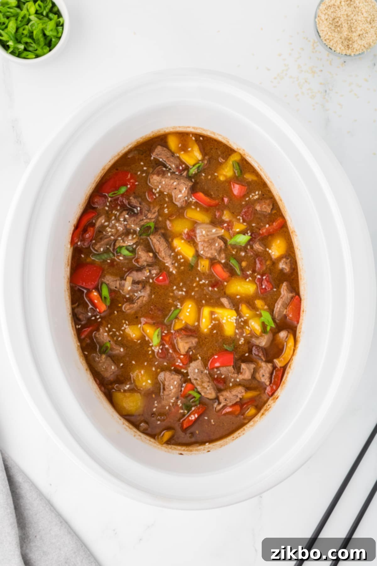 Slow Cooker Pepper Steak 11 A slow cooker filled with a saucy pepper steak and garnished with sesame seeds.