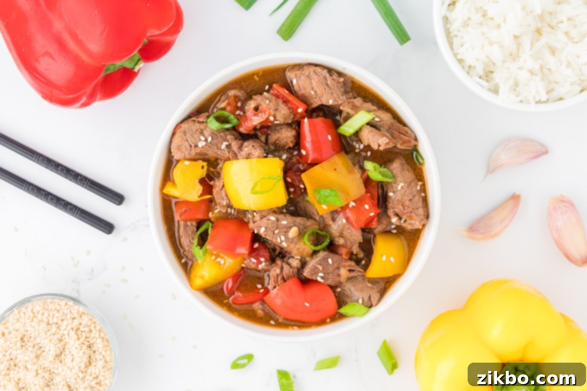 Slow Cooker Pepper Steak 13 An overhead view of a bowl of steak strips with peppers and sauce.