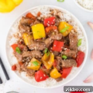 Slow Cooker Pepper Steak 16 An overhead view of a bowl of pepper steak served with rice and garnished with sesame seeds.