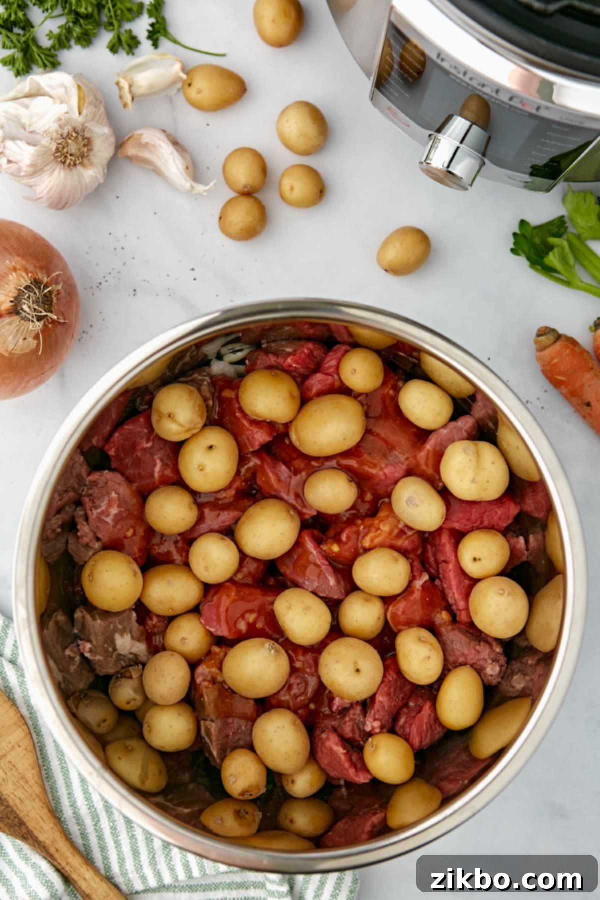 An Instant Pot filled with beef cubes, and topped with baby potatoes.