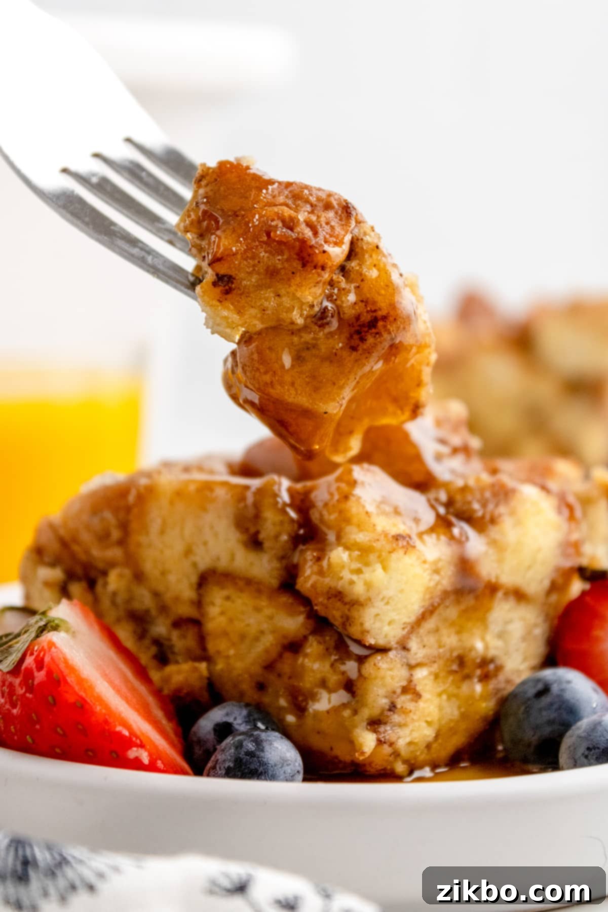 A fork piercing a soft, custardy portion of French toast casserole, ready to be lifted.