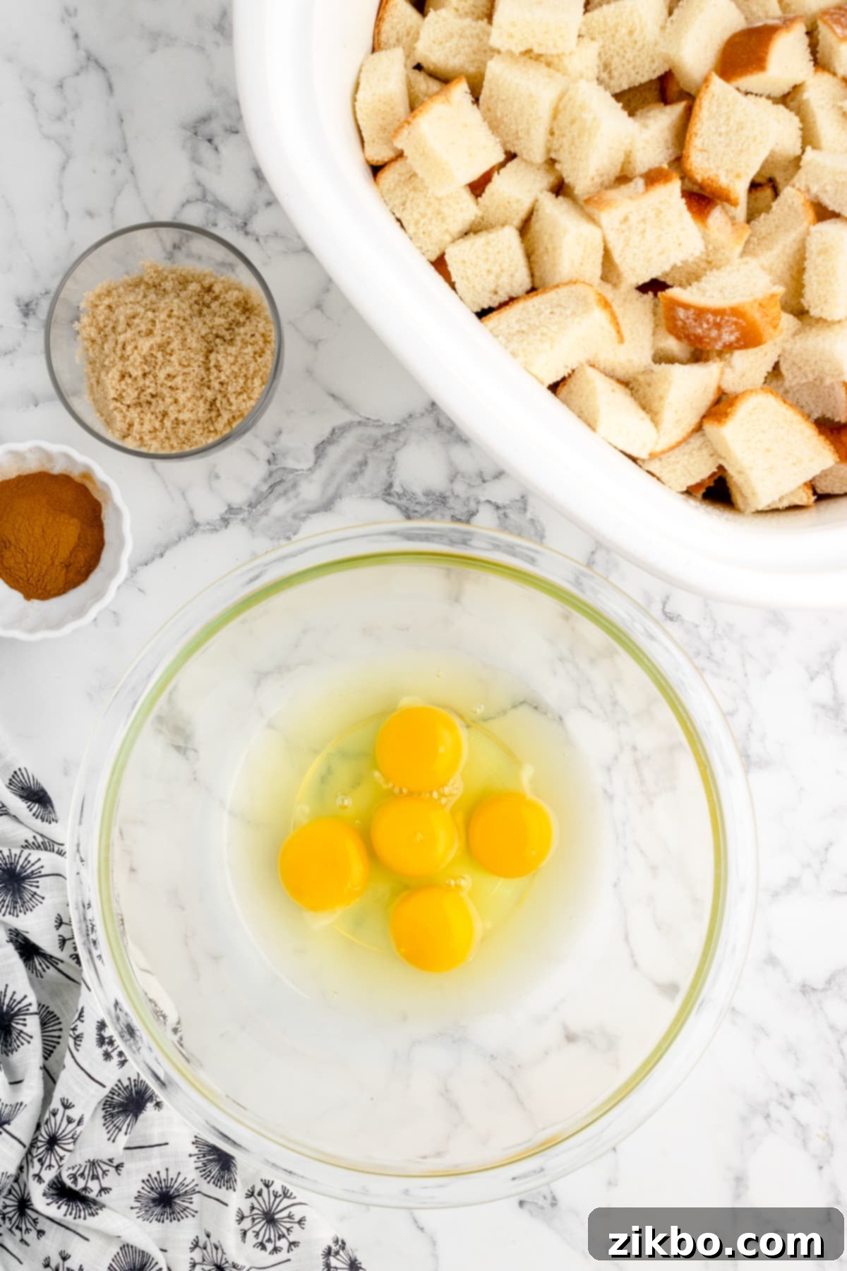 A bowl with five large eggs cracked inside, ready to be whisked for the custard mixture.