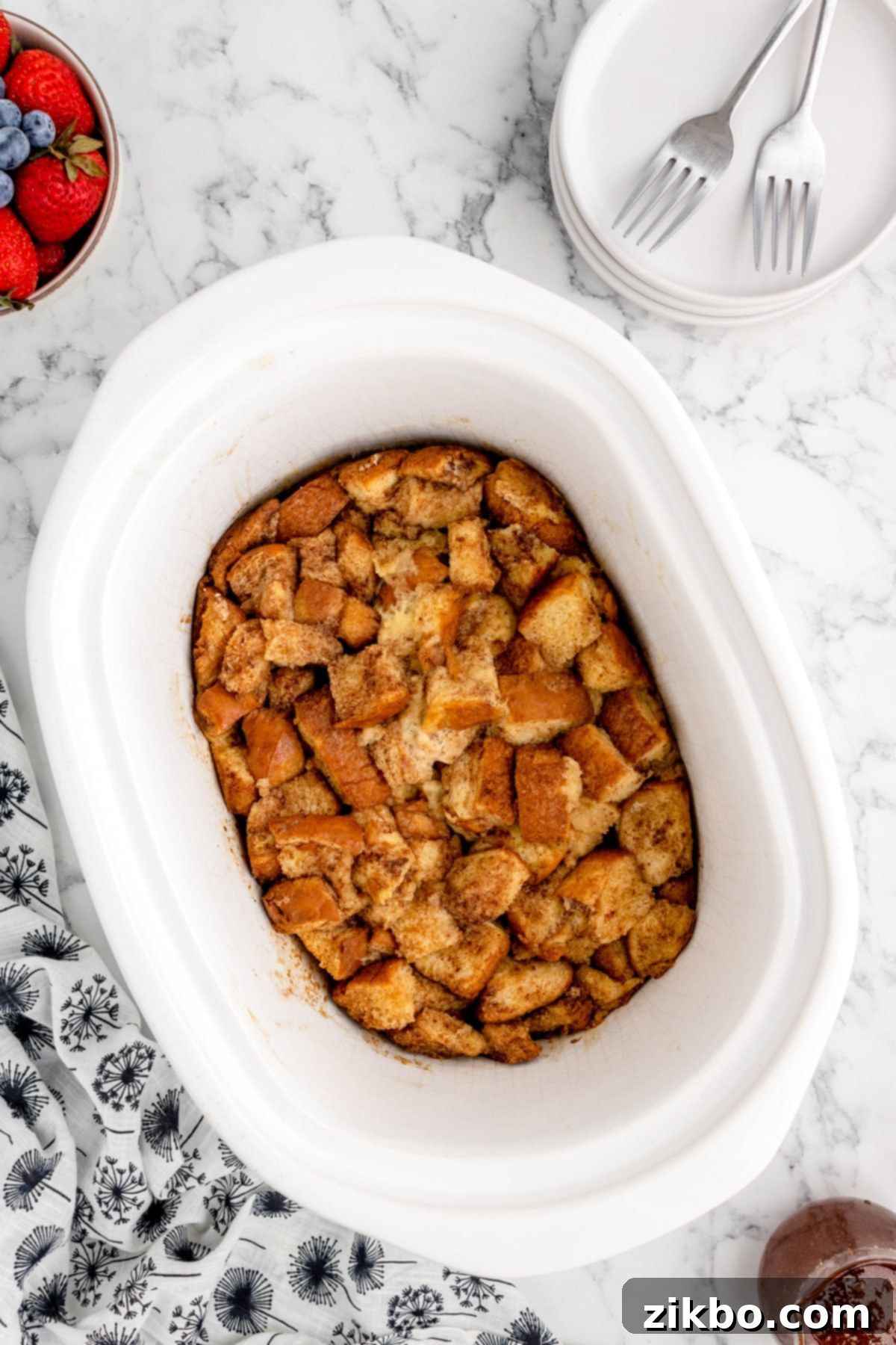 A slow cooker with a baked French toast casserole, golden brown and perfectly set.
