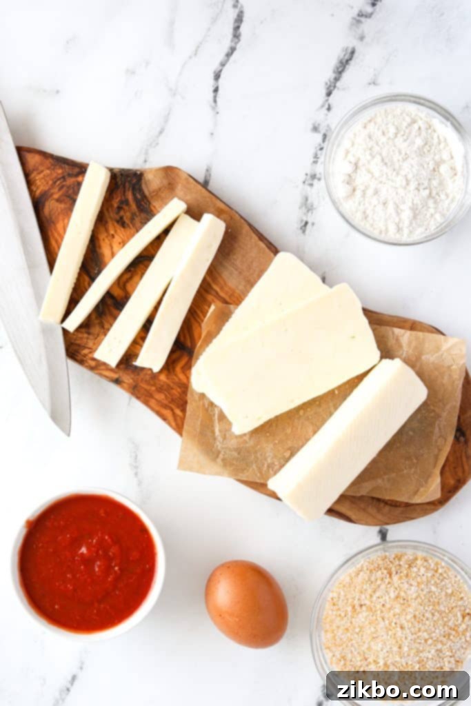 A cutting board with halloumi cheese cut into sticks, ready for breading.