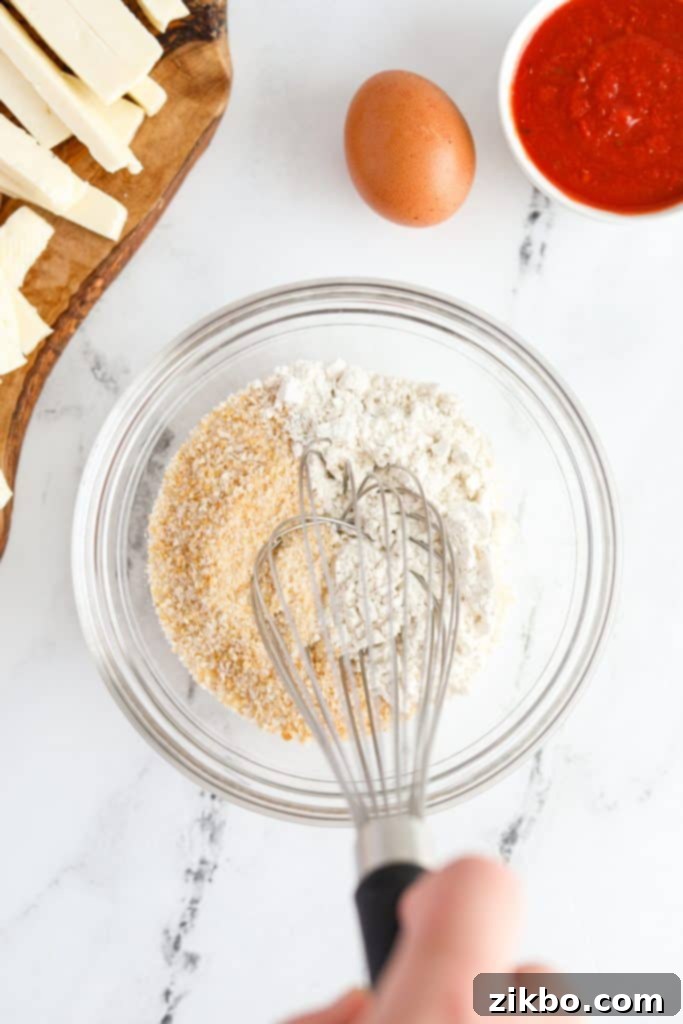 Whisking together flour and panko breadcrumbs in a medium-sized bowl to create the dry coating for the halloumi fries.
