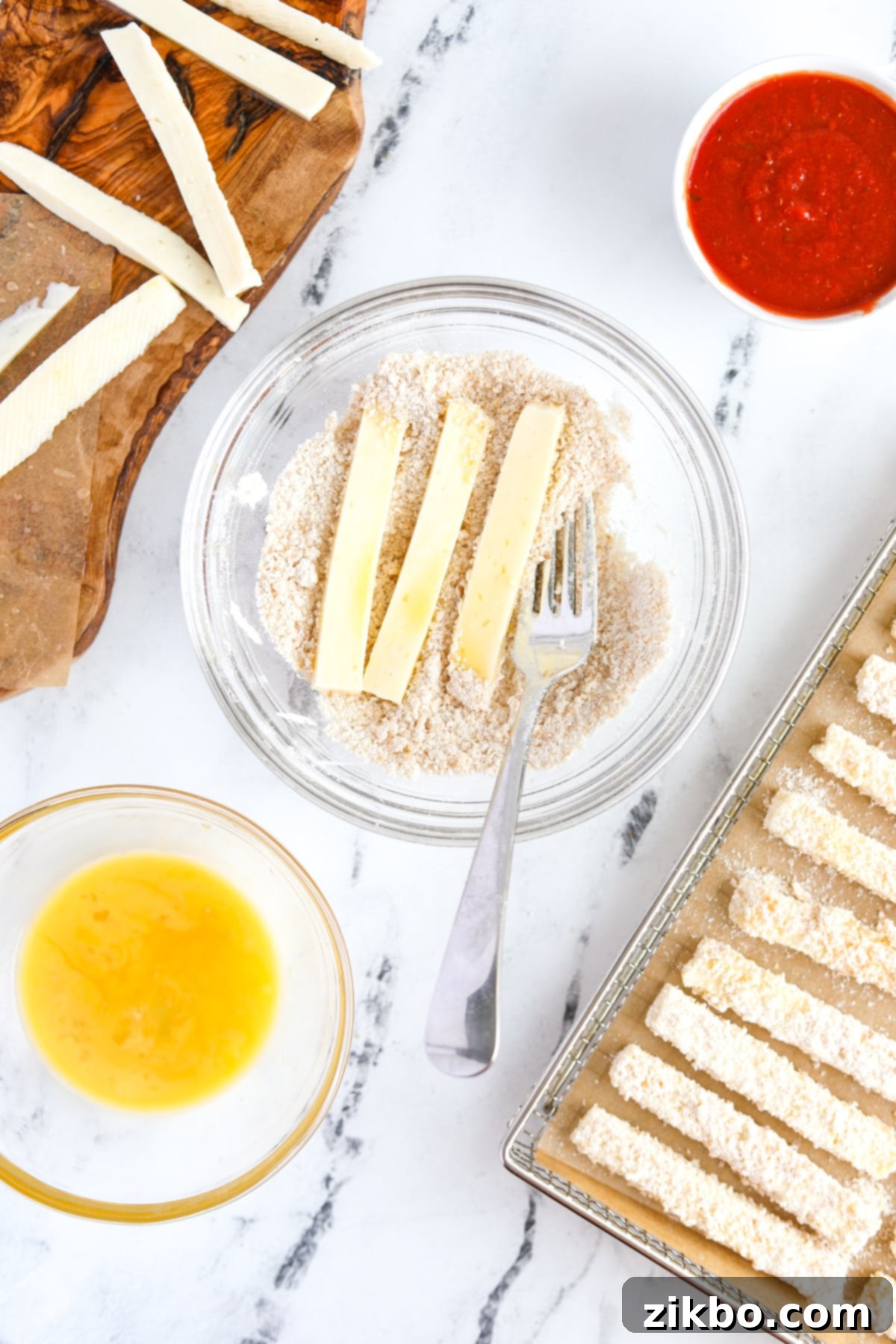 Tossing cheese sticks in a breadcrumb mixture, ensuring they are fully coated for a crispy finish.